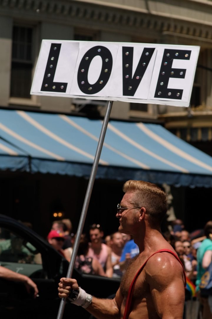 hot guy carrying a sign with the word love on it during gay pride on 9th Street Station, New York, United States