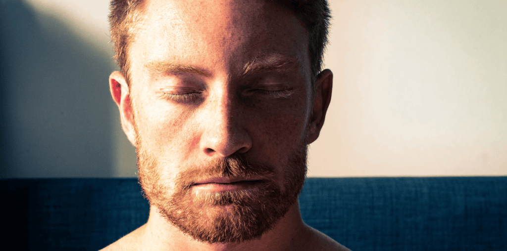 Handsome bearded man sitting with his eyes closed meditating