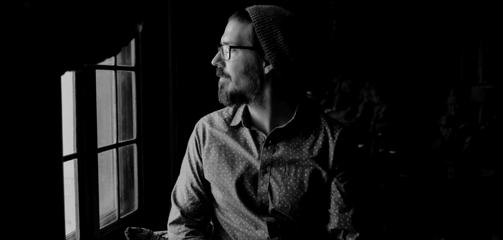 A Man Suffering from Seasonal Affective Disorder (SAD) Looking Out a Glass Window