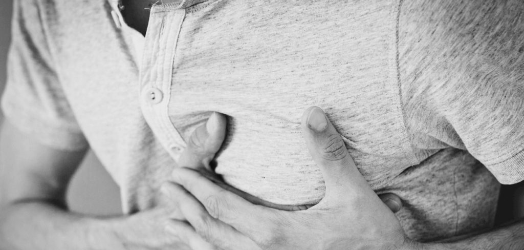 A man holding his hand his chest in pain