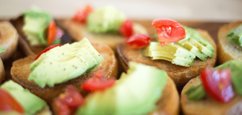 A beautiful photo of a red tomato with Avocado on top of toasted bread