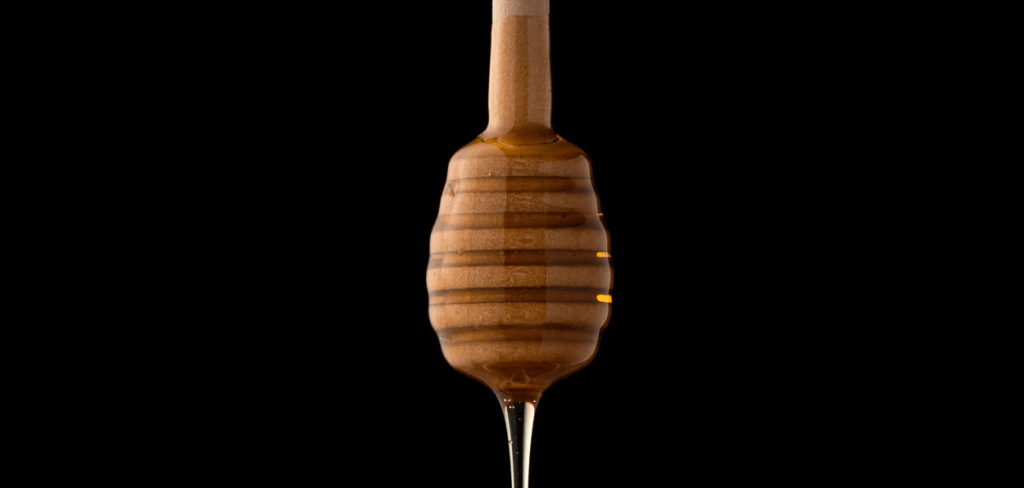 Brown wooden honey stick dipped in honey dripping