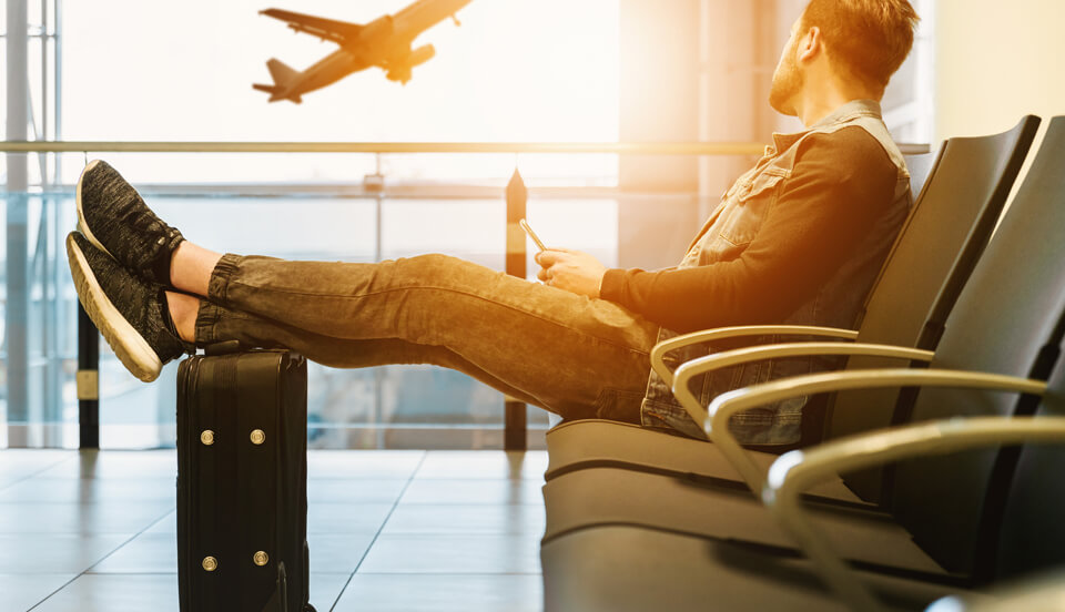 Article on Kinkster MAG about Long Distance Relationship. Handsome guy sitting in the airport watching a plane take off as the sun goes down.