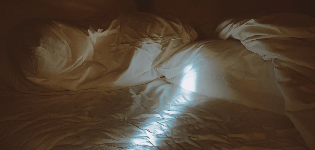 White Comforter on White Sheet and Pillows With A Ray Light Shining on the Sheets