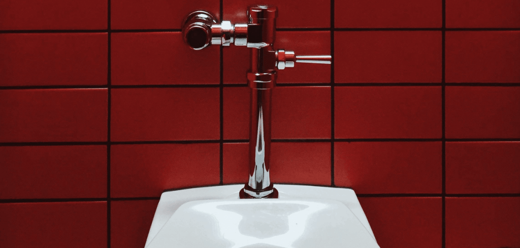 A photo of a toilet against a red tile wall