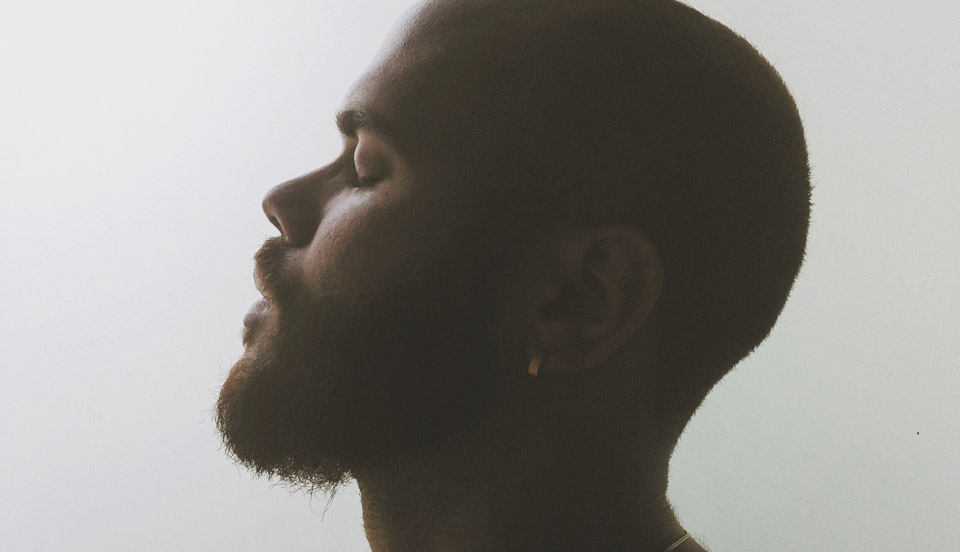 African-American male model posing with a side profile with this eyes closed facing the left