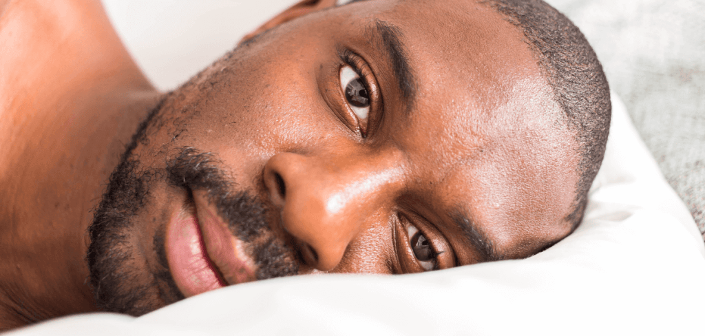 An African-American Man laying in Bed Looking Directly in the Camera