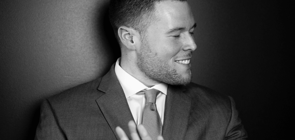 A handsome man smiling with his turned in a gray suit jacket