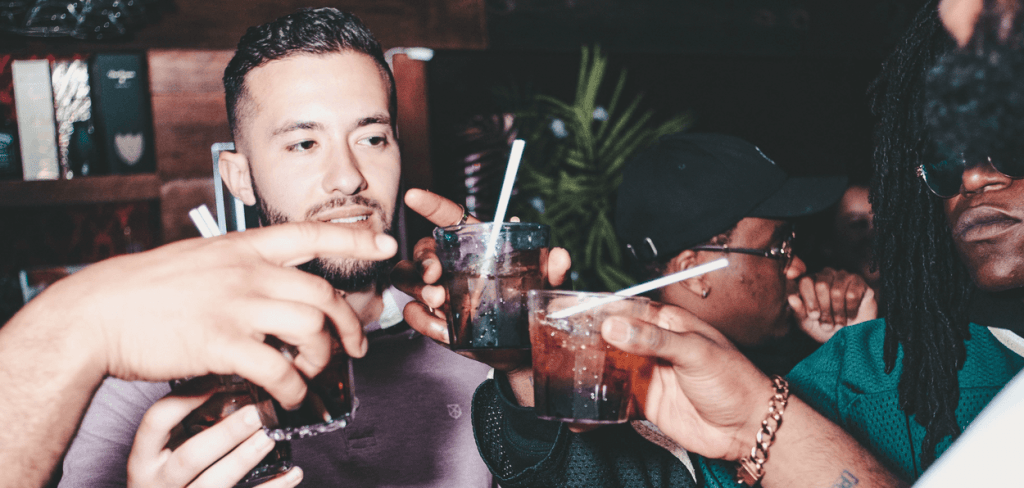 A group of hip-hop guys at a bar drinking making a toast before getting a hangover