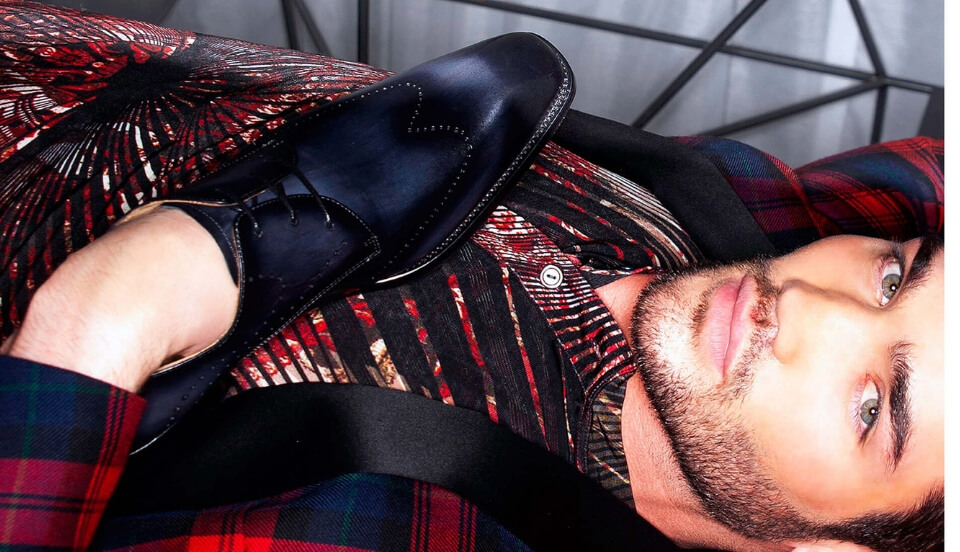 Model Chris Fawcett laying in a beautiful cranberry suit posing with a Top Owen's Black Shoe
