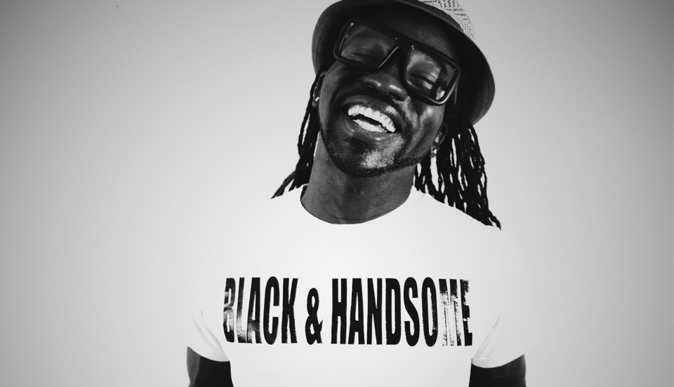 A photo of The Misunderstood Social Worker wearing a white t-shirt with black text, black & handsome!