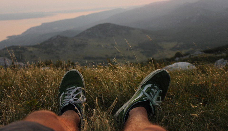 man's legs stretched out while laying on grass overlooking scenery