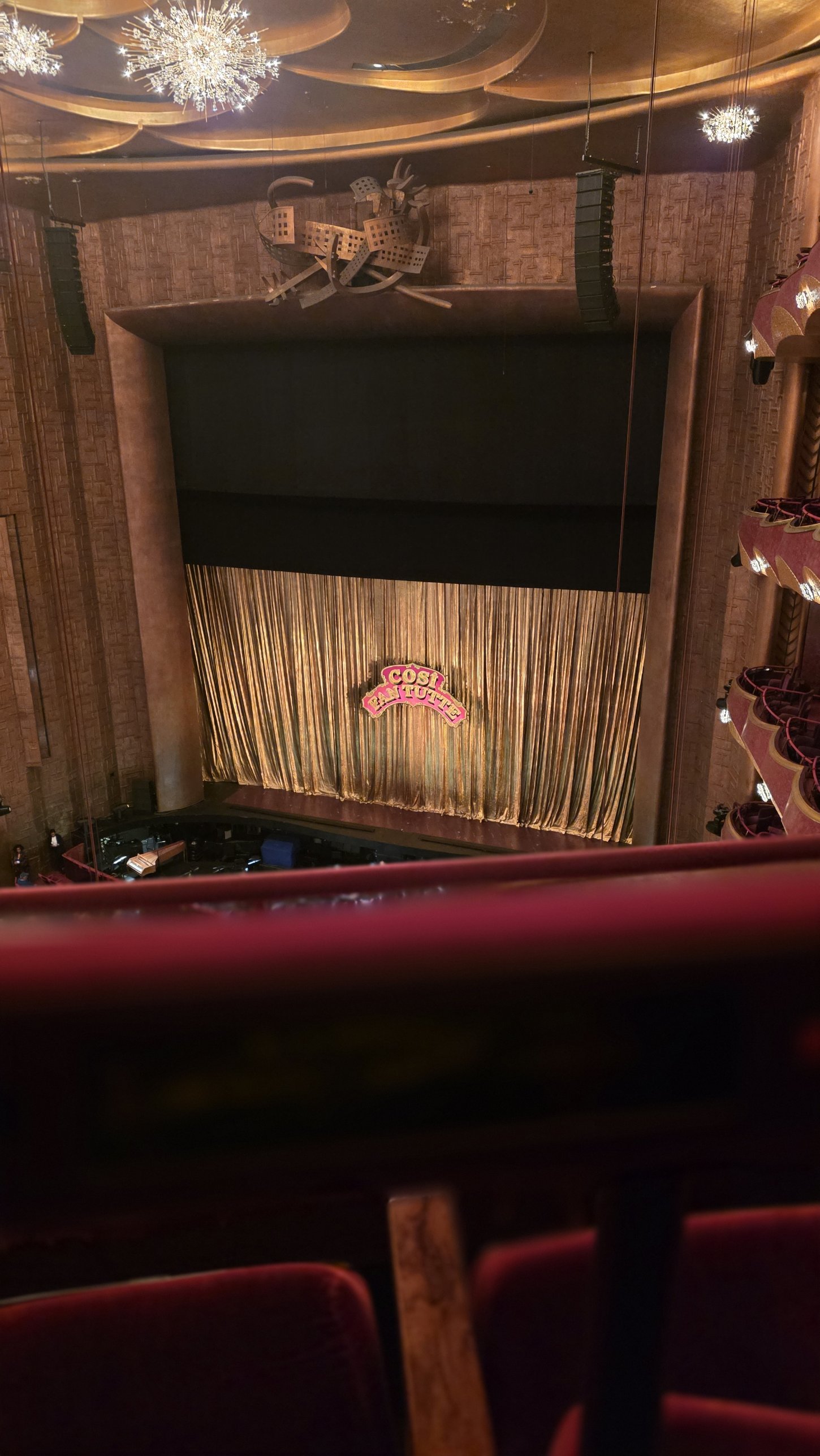 The gold curtain and Così fan tutte sign on the Metropolitan Opera stage, seen from the balcony